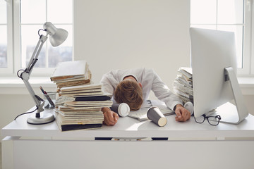 Tired busy businessman sleeping at a table with a computer.