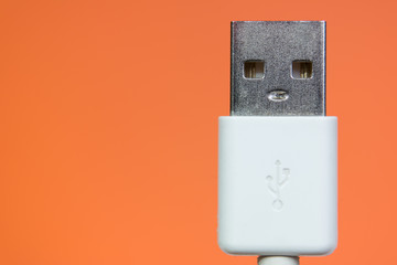The face of usb cord head like a live robot on a orange background close up