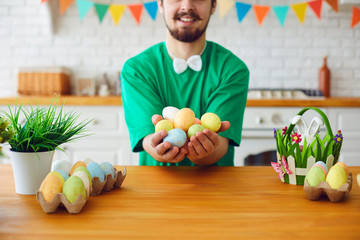 Fototapeta premium Happy Easter. A funny bearded man holds eggs in his hands and sits in the decorated room with the ears of a rabbit.
