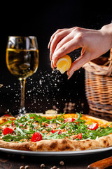 Italian Cuisine. Thin pizza with thick sides. Pizza in tomato sauce with capers, arugula, Parmesan cheese, cherry tomatoes and cod fish liver. background image, copy space text