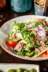 Spanish cuisine. Fish salad of mix salad, cherry tomatoes, quail eggs, capers, avacado, arugula, tuna. Serving dishes in a restaurant in a white plate. background image, copy space