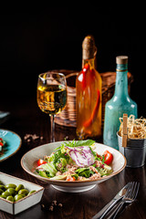 Spanish cuisine. Fish salad of mix salad, cherry tomatoes, quail eggs, capers, avacado, arugula, tuna. Serving dishes in a restaurant in a white plate. background image, copy space