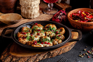 Georgian cuisine. Baked champignons with meat, cheese, parsley and pomegranate. Serving in a restaurant in an iron pan. background image, copy space