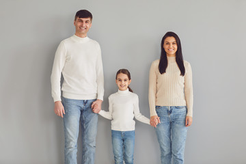 Fototapeta premium Happy family smiling while standing against gray background.