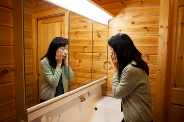 身だしなみのチェックをする高齢の女性