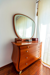 an elegant dressing table made of expensive lacquered wood with a semicircular mirror. There are beautiful boxes on the table