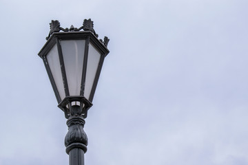 Fototapeta na wymiar Vintage street lamp. Black paint with exfoliation. Background sky.