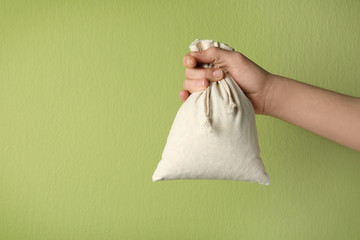 Woman holding full cotton eco bag on light green background, closeup