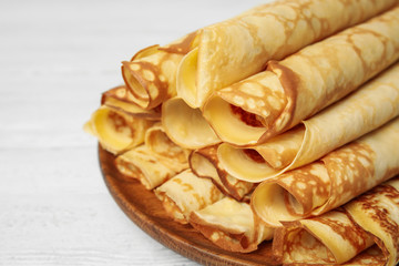 Fresh thin pancakes on white wooden table, closeup
