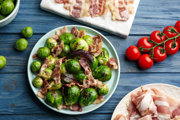 Delicious Brussels sprouts with bacon on blue wooden table, flat lay