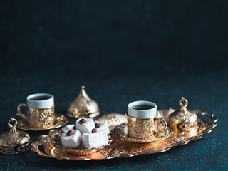 Turkish coffee with delight and traditional copper serving set on dark background. Assorted...