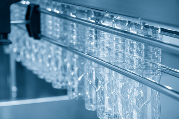 The PET bottles hanging on  the rail on the conveyor belt for filling process in the drinking water factory. The drinking water factory production process by automatic filling machine in the plant.