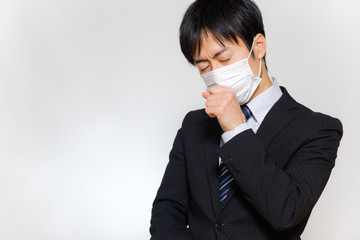 マスクをした体調不良の男性　スーツ　風邪　コロナウイルス　インフルエンザ