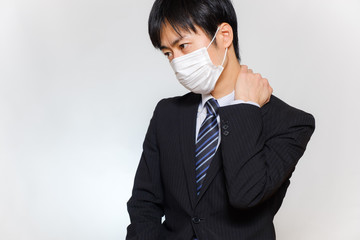 肩こりに悩むスーツ姿の男性　体調不良　しんどい