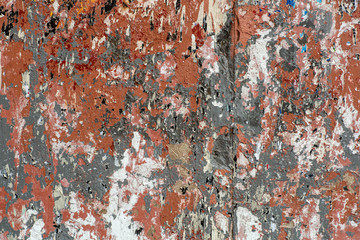 Wall with traces of old peeling paint, torn paper and glue background. Texture of a dirty street wall with torn ads and posters