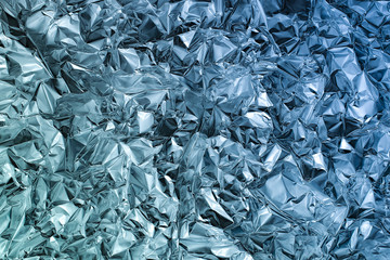 Shiny crumpled metal foil as blue background or texture