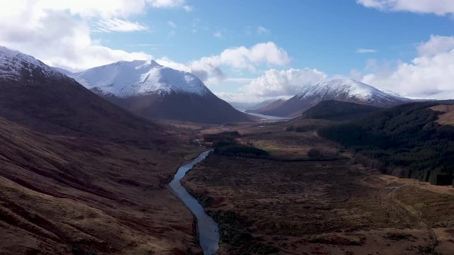 aerial drone footage of winter in glen etive in the argyll region of the highlands of scotland showing clear bright white snow on the mountains of glencoe and the surrounding region
