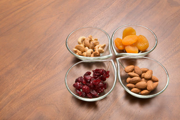 dried apricot, cranberry, almond and cashew in glass dish on wooden table
