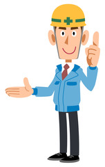 人差し指を立てて右側を紹介する建築現場の男性