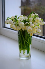 Snowdrops in a glass on the window First spring flowers