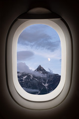 Beautiful high mountains peak in clouds in frame window plane