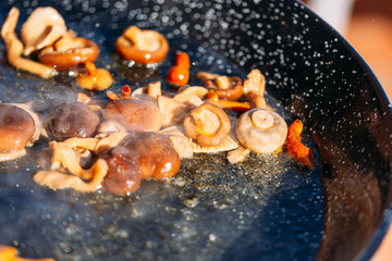 Fototapeta na wymiar pan with mushrooms frying with hot oil in the foreground