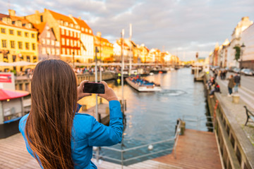 Fototapeta na wymiar Copenhagen Denmark travel tourist woman taking photo of Nyhavn water canal old town famous tourism destination, attraction in scandinavia, Europe.