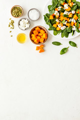 Cooking salad with pumpkin and basil. Ingredients on white background top-down copy space