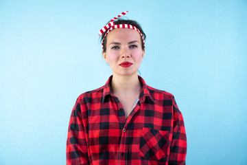 Fototapeta premium Lovely woman retro portrait with pin-up make-up and hairstyle. Red shirt. Blue background