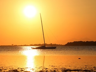 sailboat moored on the sea at sunset and headland on the background