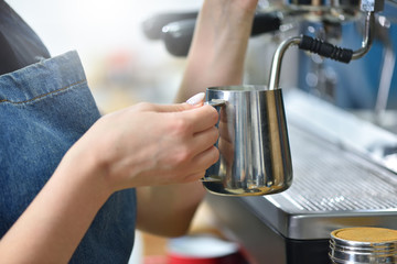 Bartender prepare coffee on a coffee machine and whips milk with steam, hands closeup. Small business concept