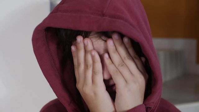 Close-up of a child hiding her face while crying.