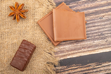 Chocolate and star anise on a background of rough homespun fabric. Close up.