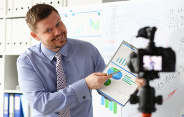 Male in suit and tie show stats graph pad making promo videoblog or photo session in office...