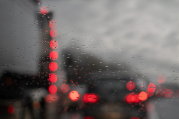View from a car on a traffic jam on a rainy gloomy day, Raindrops on the glass in focus, commuters cars out of focus. Concept heavy urban traffic.