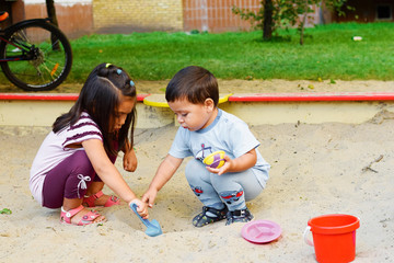Naklejka premium Latin kids playing with sand in sandbox.