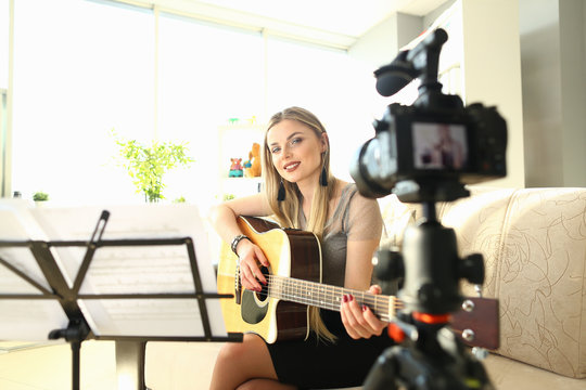 Female Blogger Creating Art Musical Vlog Content. Caucasian Woman Sitting at Living Room Playing Acoustic Guitar. Dreamy Girl Filming Practice Tutorial. Smiling Girl Perform Romance