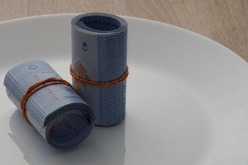 image of a rolls of  banknote in a white plate. bribery concept