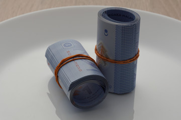image of a rolls of  banknote in a white plate. bribery concept