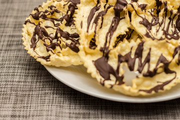 Bugie with chocolate, a traditional italian carnival fritters on white plate.