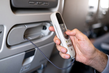 Closeup LCD rear seat on the plane technology for entertainment. Passenger traveling by a commercial aircraft controls by remote control entertainment system. Intercontinental flight.