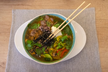Ramen noodles soup in bowl with chopsticks.