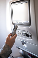 Closeup LCD rear seat on the plane technology for entertainment. Passenger traveling by a commercial aircraft controls by remote control entertainment system. Intercontinental flight.