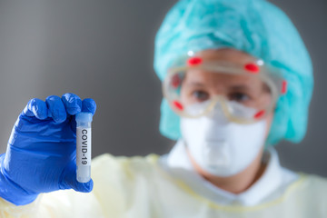 Frau mit Schutzmaske im Labor untersucht eine Probe mit Covid-19 (Coronavirus)