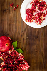 Juicy pomegranate with seeds on plate on dark wooden table top-down copy space