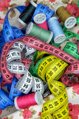 measuring tape and spools of thread on fabric background