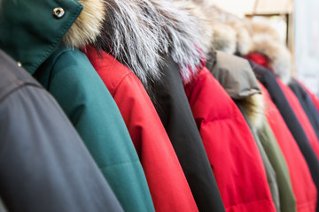 assortment of winter jackets and down jackets on store hangers. - 328465343
