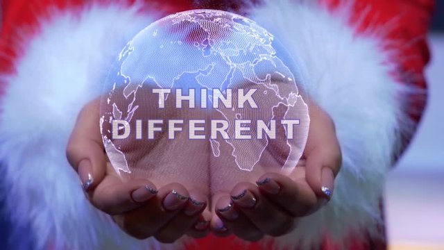 Female hands holding a conceptual hologram of planet Earth with text Think different. Woman in red clothes with faux white fur with future holographic technology