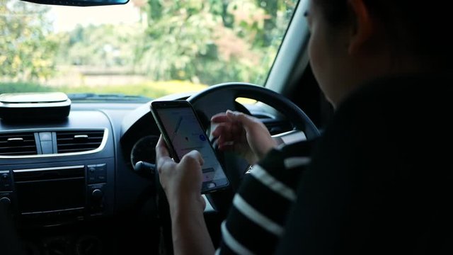 Asian young woman using the Google Maps application on a smartphone to search for directions while driving. Concept of using technology in transportation.