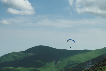 Paraglider flying over mountains in summer day